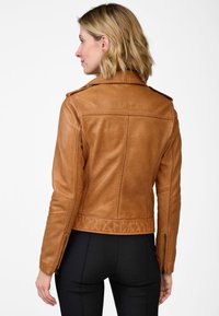 Bruine leren jas met een aansluitend ontwerp, ritsmanchetten en schouderklappen. Glad textuur met zichtbare stikseldetails.