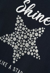 T-Shirt aus marineblauem Stoff mit einem silbernen Glitzerstern-Design aus verschieden großen Punkten, mit dem Wort "Shine" darüber und "LIKE A STAR" darunter.