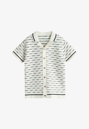 Maglietta in maglia bianca a maniche corte con motivo a righe orizzontali punteggiate nere, chiusura frontale con bottoni e colletto con bordo nero.