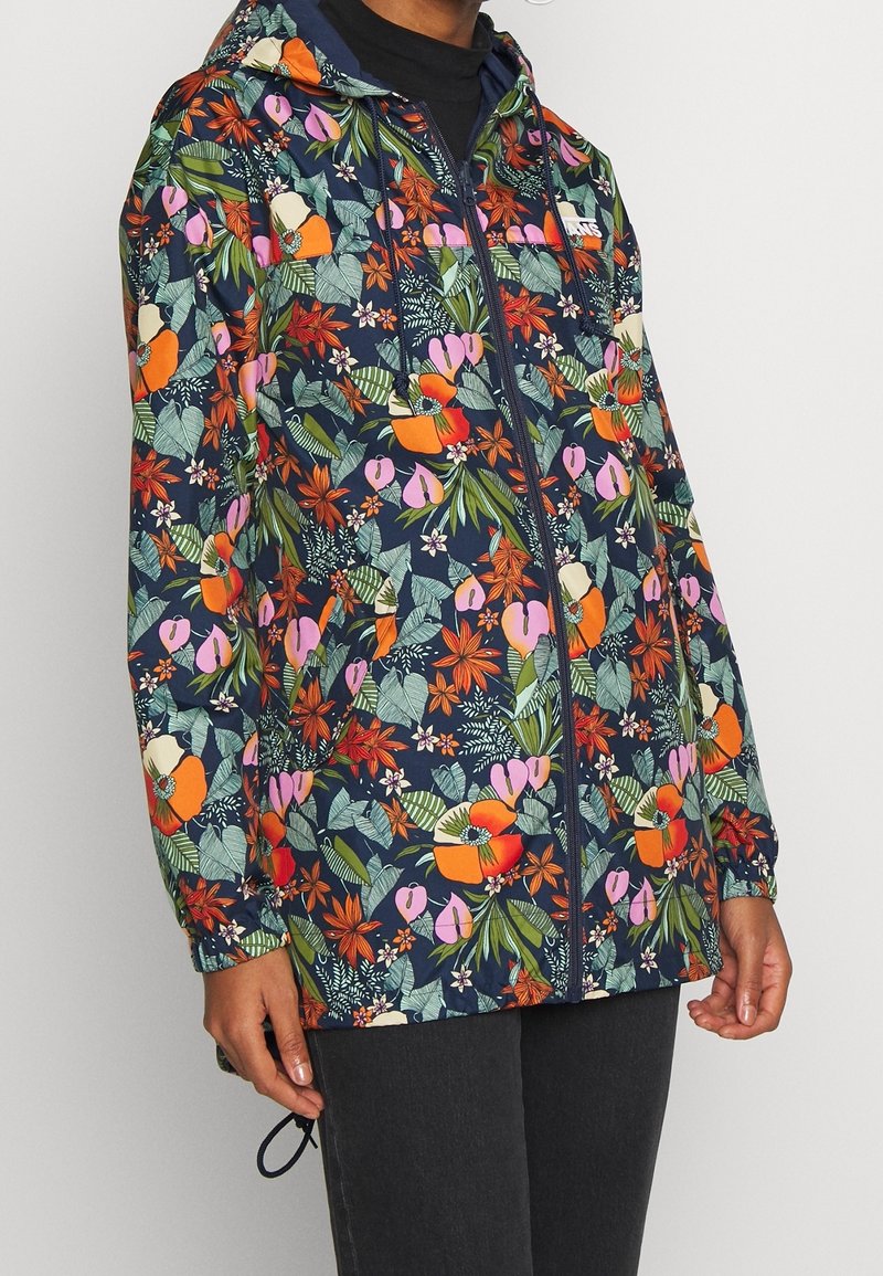 Granatowa kurtka w kwiaty, z mieszanką żywych pomarańczowych, różowych i zielonych kwiatów. Wykonana z lekkiego materiału, z zamkiem błyskawicznym i kapturem.