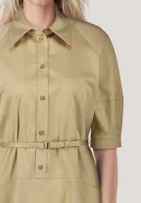 Khakifarbene Hemdkleid mit Kragen, Knopfverschluss und kurzen Ärmeln. Es hat eine taillierte Taille mit einem Gürtel und besteht aus glattem, strukturiertem Stoff.