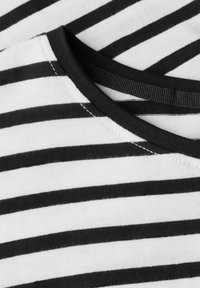 Tela de rayas en blanco y negro con una textura suave y un escote redondeado, que presenta un ribete acanalado oscuro a lo largo del cuello.