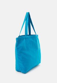 Μπλε υφασμάτινη τσάντα tote με δύο μακριές, ανθεκτικές λαβές, με ορθογώνιο σχήμα και απαλό υλικό, σχεδι�ασμένη για καθημερινή χρήση.
