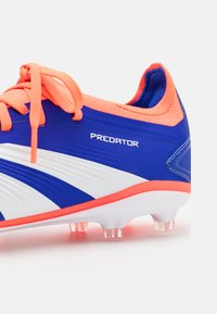 Blauwe en witte voetbalschoenen met oranje veters, gestructureerde synthetische bovenkant, rubberen buitenzolen en zichtbare branding "PREDATOR."