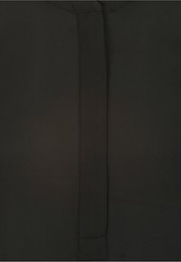 Blusa negra con una textura suave, que presenta una costura vertical central y un sutil cierre de botón en el cuello. Diseño y forma clásica.