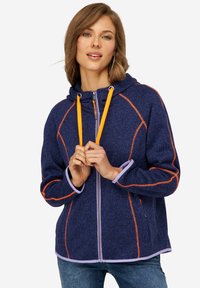 Veste à capuche navy avec des coutures orange et lavande, fermeture éclair à l'avant et deux poches latérales ; fabriquée en tissu texturé.