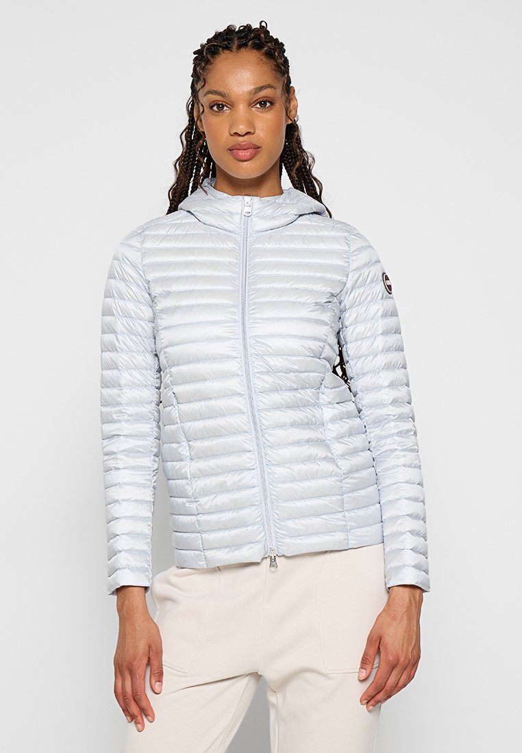 Giubbotto imbottito blu chiaro con texture a righe orizzontali, zip frontale e cappuccio. Presenta una patch con il logo sulla manica sinistra.