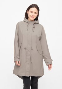 Lichtgrijze waterdichte jas met een capuchon, trekkoord in de taille en voorzakken. Heeft lange mouwen en een iets langere achterkant.