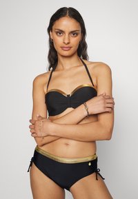 Biquíni preto com detalhes em dourado. O top apresenta um design sem alças e um nó decorativo. A parte de baixo tem uma faixa dourada e laços laterais.