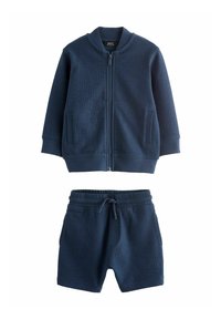 Marineblå jacka och shorts-set i strukturerad tyg. Jackan har dragkedja fram och två sidofickor; shortsen har resårmidja.