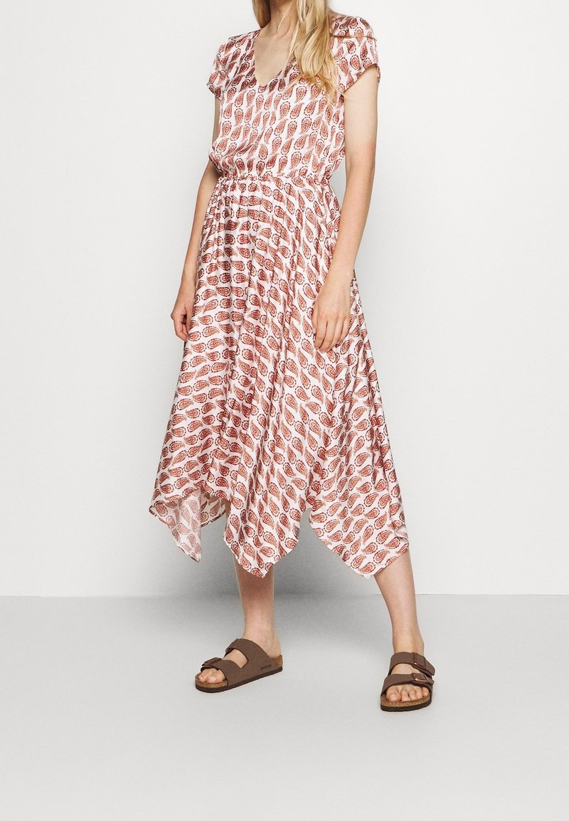 Vloeiende jurk met een v-hals, korte mouwen, rood-wit loofpatroon, cinched taille, asymmetrische zoom, gecombineerd met bruine sandalen.
