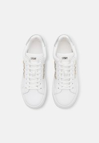 Baskets blanches en cuir lisse avec des accents argentés au talon et un détail de logo métallique. Elles sont dotées de lacets plats et d'un bout arrondi.