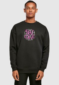 Felpa nera con maniche lunghe, collo giro, e una grande grafica in rosa e bianco con la scritta "STAY CALM" al centro. Texture morbida.