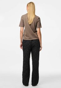 Bruine short-sleeve shirt gecombineerd met zwarte, tekstuurrijke wijde broek, die een gekreukt patroon en een ontspannen pasvorm laat zien.