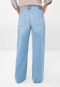 Jeans a gamba larga di colore azzurro chiaro, caratterizzati da una texture liscia, un classico design a cinque tasche e dettagli di cucitura sottili sulle tasche posteriori.
