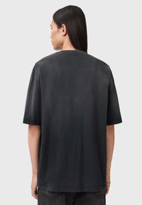 Zwart katoenen T-shirt met korte mouwen en een ronde hals. Glad oppervlak, losse pasvorm en een minimalistisch ontwerp zonder zichtbare patronen of logo's.