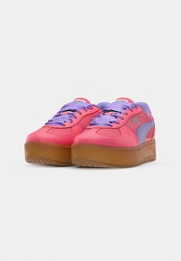 Różowe skórzane sneakersy z fioletowymi sznurówkami, grubą gumową podeszwą i bocznym akcentem z logo. Okrągły czubek i wyściełany język dla wygody.