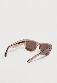 Brown-tinted sunglasses with transparent frames, featuring a geometric shape and sleek design. Accented with subtle metallic detailing.