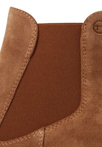 Braune Wildleder-Ankle-Boots mit elastischen Seitenteilen, kontrastierender Textur und gesteppten Details. Glatte Oberfläche mit abgerundetem Oberrand.