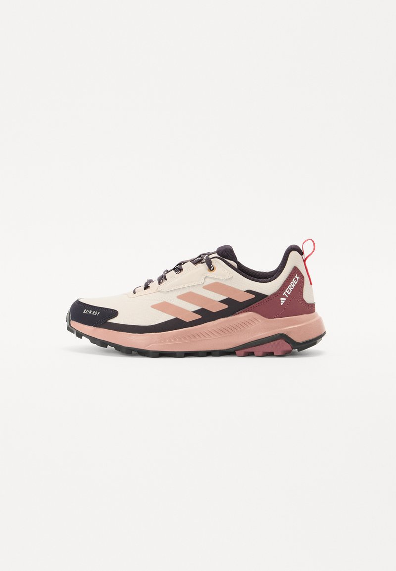 Fjellsko for løping med en lys beige mesh-overdel, rosa detaljer, svart gummisåle og en trekkstrop bak hælen.