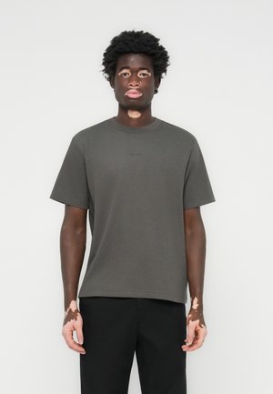 Korte mouwen, ronde hals t-shirt in donkergrijs katoen met een relaxte pasvorm. Heeft minimale branding op de borst.