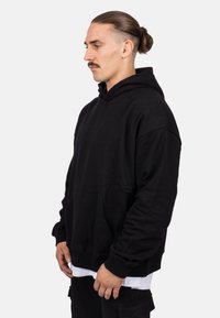 Sudadera negra con capucha y bolsillo frontal, de corte relajado y puños acanalados. Fabricada con tela suave, con un diseño simple y minimalista.
