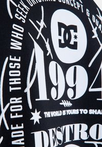 Zwarte stof met witte grafische tekst en ontwerpen. Elementen omvatten het nummer "1994", logo's en verschillende typografiestijlen.