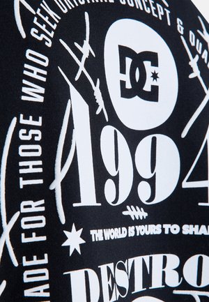 Zwarte stof met witte grafische tekst en ontwerpen. Elementen omvatten het nummer "1994", logo's en verschillende typografiestijlen.