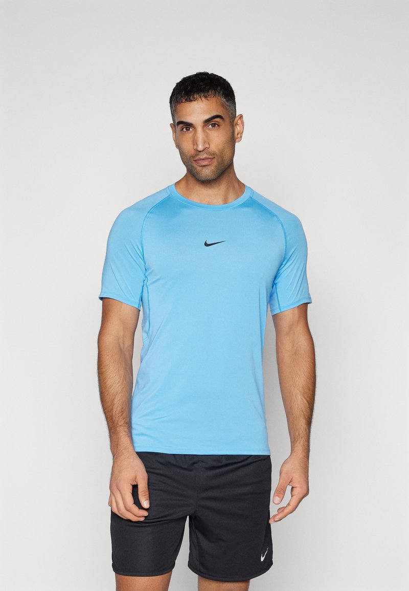 Hellblaues Sportshirt mit kurzen Ärmeln und Rundhalsausschnitt, mit einem schwarzen Nike-Logo auf der Brust. Getragen mit schwarzen Shorts.