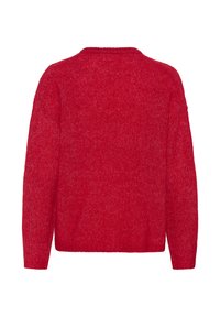 Punane kootud kampsun, mis on lõdva lõikega, varustatud ümarate kaeluse ja pikkade varrukatega. Tekstuur on pehme ning sel on õrn kirju muster.