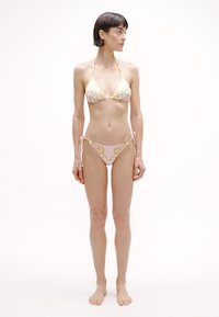 Σετ μπικίνι με τριγωνικό τοπ και χαμηλόμεσο κάτω μέρος. Τα υλικά είναι ύφασμα με κίτρινα και ροζ λουλουδάτα μοτίβα. Δέσιμο στα πλαϊνά.