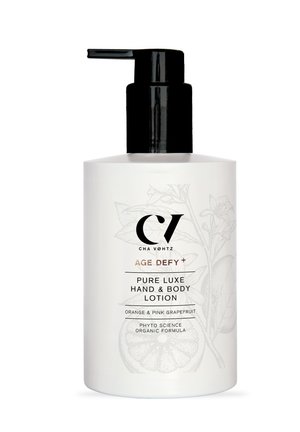 White bottle with a black pump dispenser. Label features a botanical illustration, gold accents, and text stating "Pure Luxe Hand & Body Lotion."