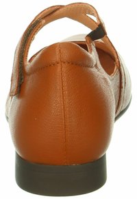 Scarpa in pelle marrone con retro arrotondato, design ritagliato e tracolla regolabile. Superficie testurizzata con un tacco basso di colore scuro.