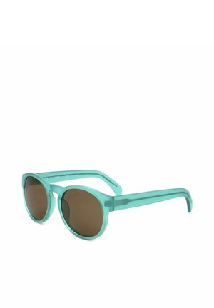 Occhiali da sole rotondi traslucidi color verde acqua con lenti marroni e stanghette spesse su sfondo bianco.