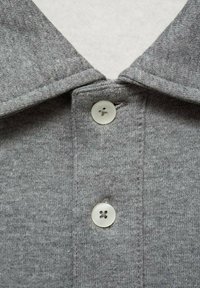 Grå bomullspolo med en texturerad yta, med klassisk krage och tre vita knappar med fyra hål.