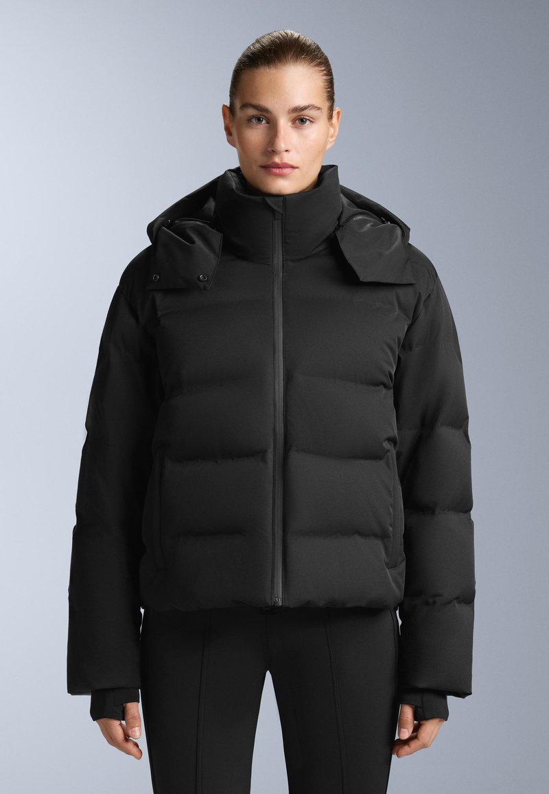 Crna puf jakna s visokim ovratnikom, zatvorenim patentnim zatvaračem sprijeda i oversized siluetom. Ima panele s punjenjem, odvojivu kapu i elastične manžete.