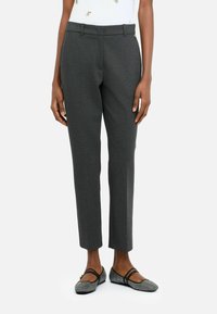 Pantaloni grigi su misura con gamba dritta, una sottile texture e passanti per la cintura, abbinati a scarpe nere basse con un motivo decorativo.