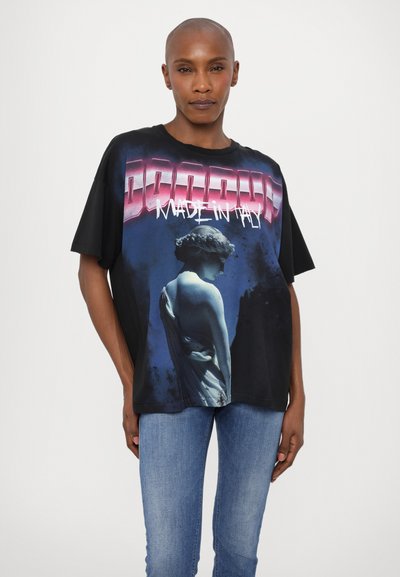 Camiseta negra de gran tamaño con un estampado gráfico de una estatua sobre un fondo azul, con el texto "HECHO EN ITALIA" en un vibrante color rosa.