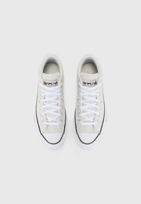 Baskets en toile blanches avec un design bas, dotées de lacets blancs, d'accents en caoutchouc noirs et d'un écusson affichant "Converse All Star."