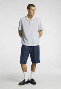 Košile s krátkým rukávem a límečkem s modro-bílým pruhovaným vzorem, kombinovaná s námořnickými šortkami. Doplněna černými botami a bílými ponožkami.