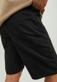 Shorts in denim nero con taglio dritto, design a cinque tasche e texture sottile. Il tessuto presenta una finitura opaca scura.