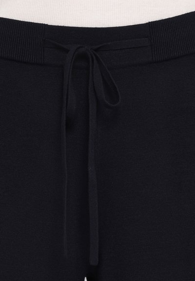 Temno modri trenirčki z teksturirano tkanino, ki imajo rebrast pas in vrvico za prilagodljivo prileganje.