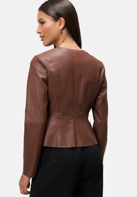 Hnedá kožená bunda s priliehavým strihom, dlhými rukávmi a peplum lemom. Má jednoduché švy a hladkú textúru.