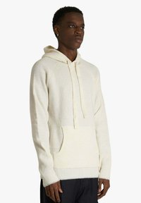 Felpa con cappuccio color crema con trama a coste, tasca frontale, cappuccio con coulisse e polsini aderenti. Realizzata in materiale morbido con una vestibilità rilassata.