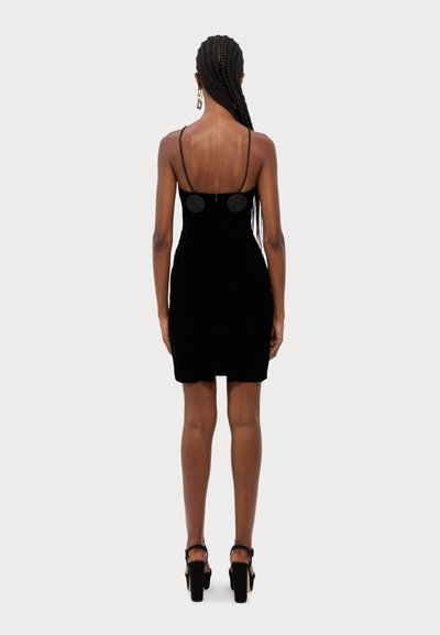 Rochie mini din catifea neagră cu bretele subțiri ajustabile, caracterizată printr-un fermoar la spate și accente circulare pe spate, design simplu.