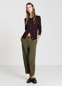 Cardigan color bordeaux con bottoni dorati, abbinato a pantaloni larghi verde oliva e mocassini marrone scuro. Texture liscia e vestibilità rilassata.