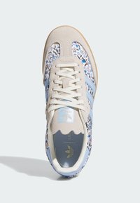 Sneaker mit einer strukturierten, hellgrauen Wildlederspitze, einem blau blumenmusternden Textiloberteil und hellblauen synthetischen Streifen, ausgestattet mit beigen Schnürsenkeln.
