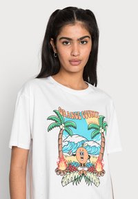 T-shirt branca de algodão com um design gráfico colorido, apresentando palmeiras, ondas e um personagem de desenho animado segurando uma laranja.