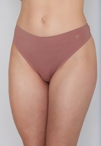 Rose-colored bikini bottoms made of smooth fabric, featuring a low-rise cut and minimal stitching, with a small logo accent on the side.