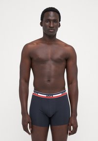 Boxer shorts negros con una cinturilla de logo de Levi's en blanco y rojo. Textura suave, diseño ajustado y longitud hasta medio muslo.